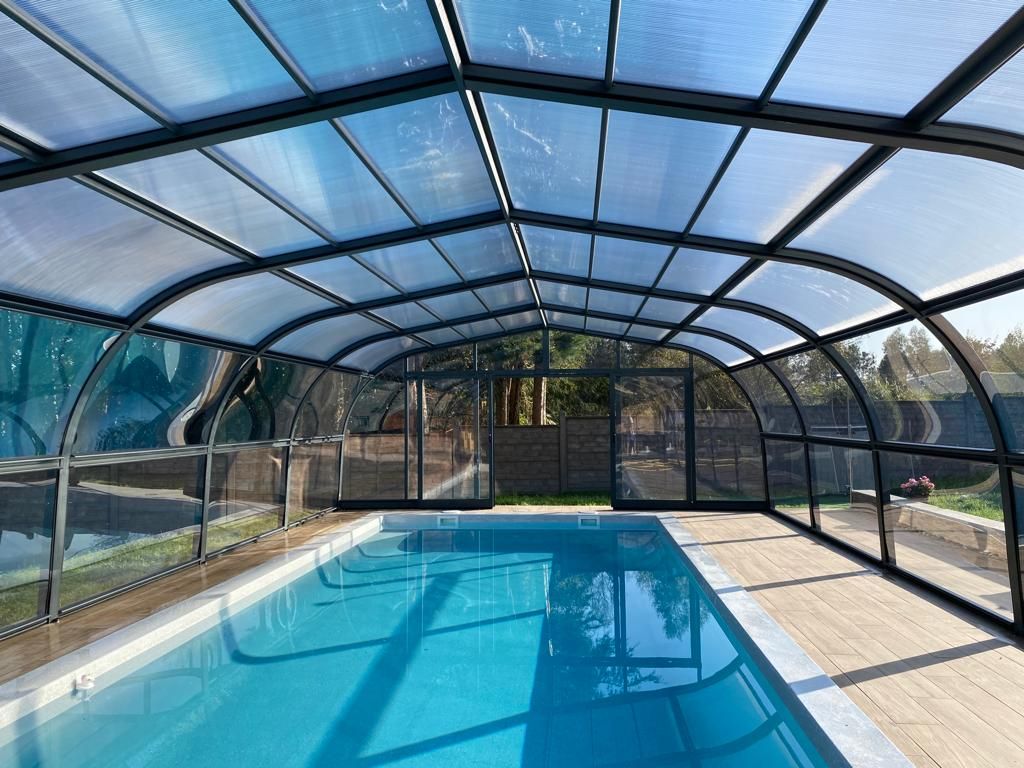 Una gran piscina cubierta bajo un techo transparente.
