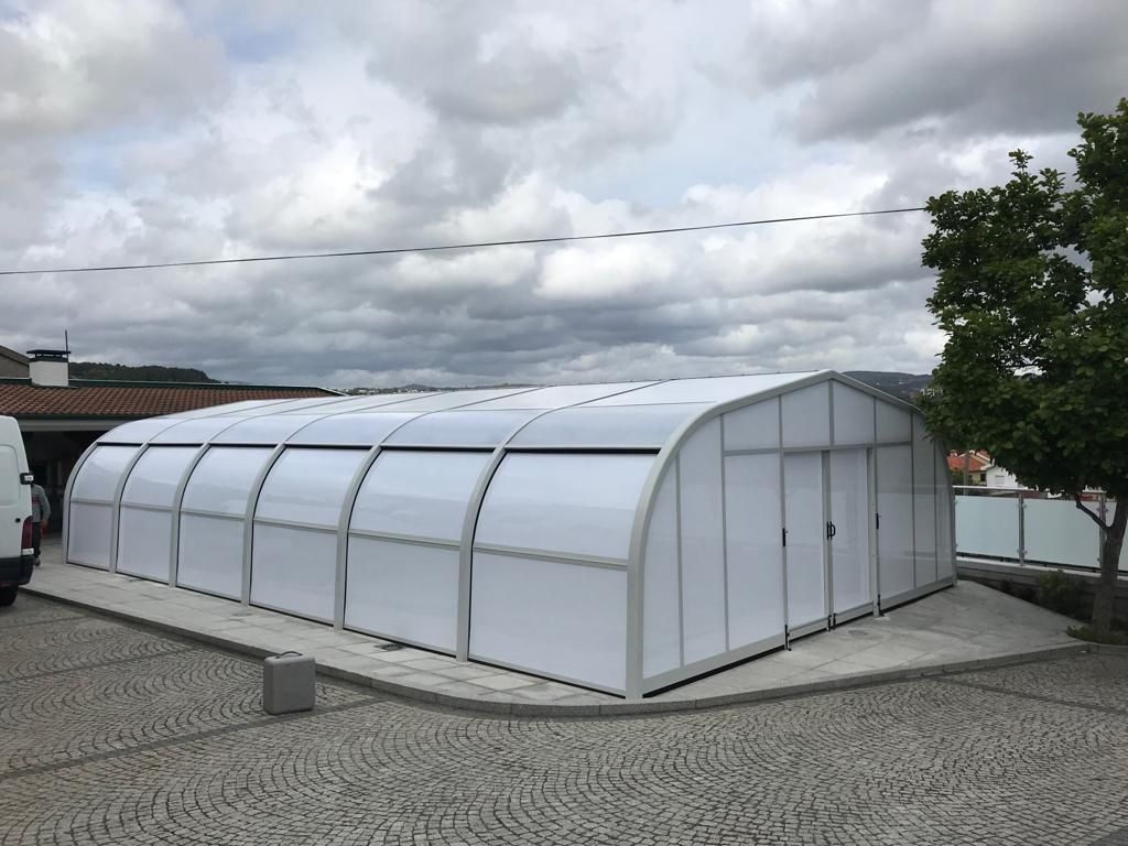 Un gran invernadero blanco se encuentra encima de un camino adoquinado.