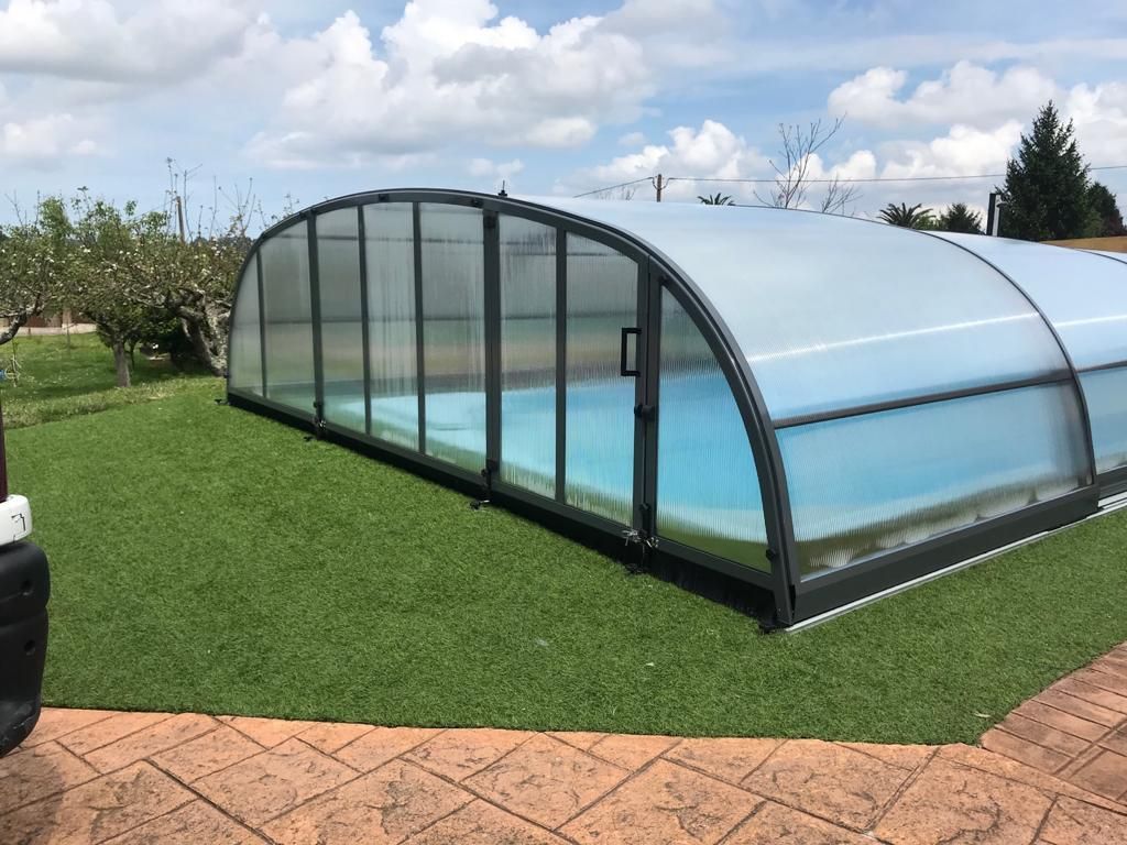 Una piscina con cubierta se encuentra encima de un exuberante césped verde.