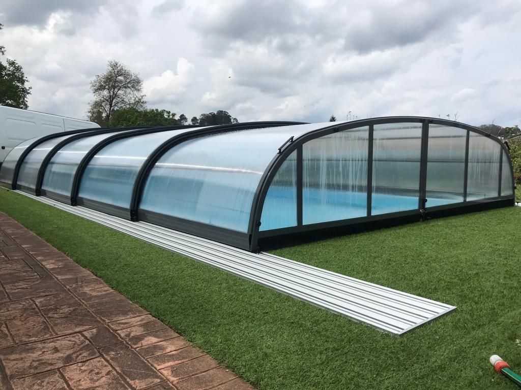 Una gran piscina cubierta se encuentra encima de un exuberante campo verde.