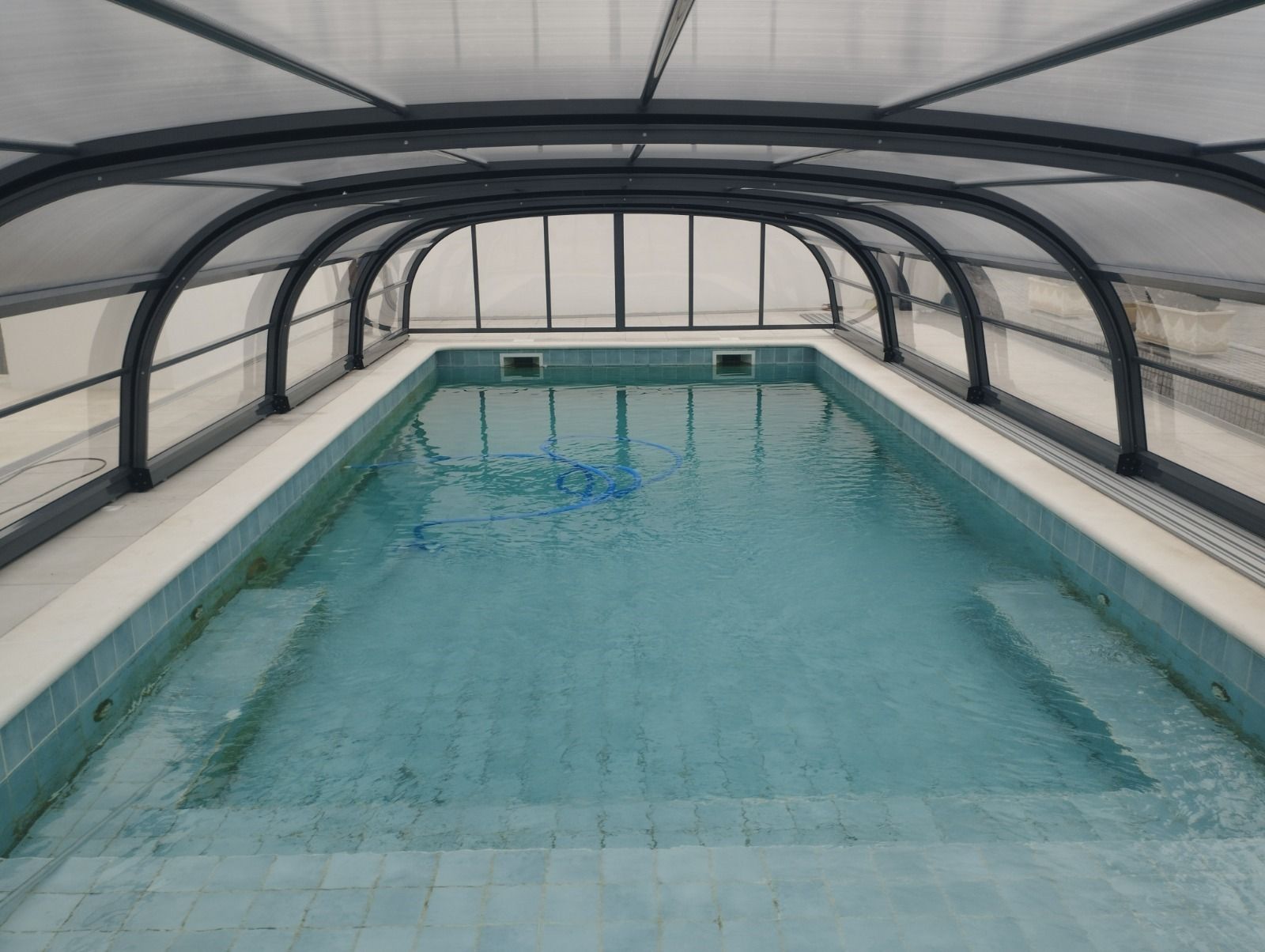 Una gran piscina está bajo un techo transparente.