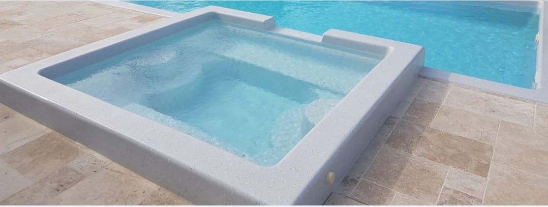 Hay un jacuzzi al lado de una piscina.