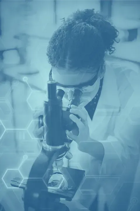 Una mujer está mirando a través de un microscopio en un laboratorio.