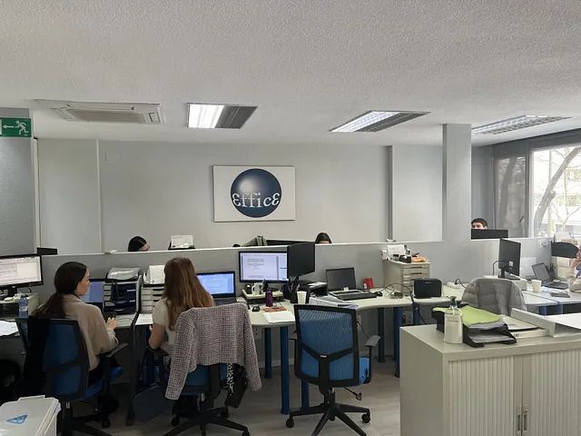 Un grupo de personas están sentadas en escritorios en una oficina.