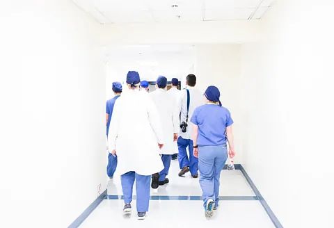 A group of doctors and nurses are walking down a hospital hallway.