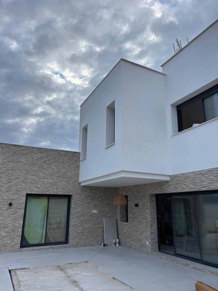 Edificio de hormigón en construcción, parcialmente construido, con andamios y materiales en la obra