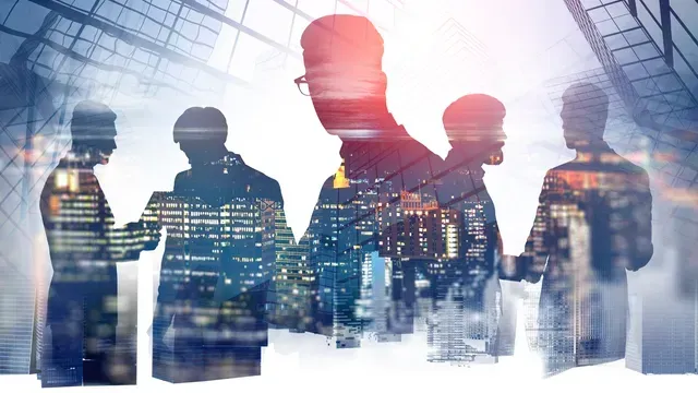 Un gruppo di persone si stringe la mano di fronte allo skyline di una città.