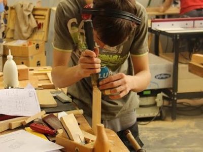Un uomo sta lavorando su un pezzo di legno con una bomboletta di lubrificante in mano