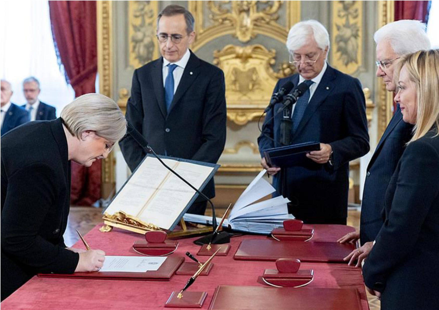 Una donna sta firmando un documento davanti a un gruppo di uomini
