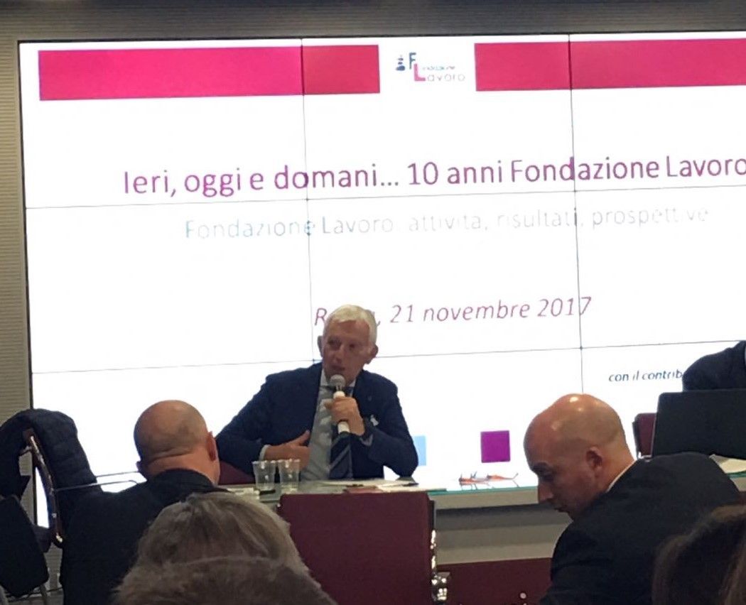 A man is giving a presentation in front of a screen that says ieri oggi e domani 10 anni fondazione lavoro