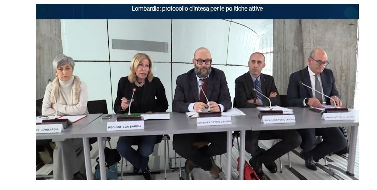 Un gruppo di persone è seduto a un tavolo con dei microfoni.