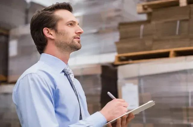 Un uomo sta scrivendo su una lavagna in un magazzino.