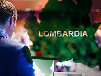 Un uomo in giacca e cravatta guarda una mappa della Lombardia.