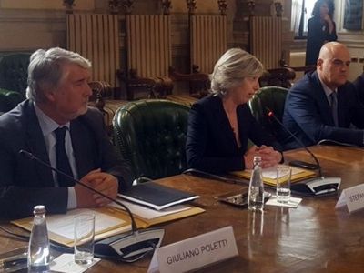 Un gruppo di persone è seduto a un tavolo con dei microfoni.