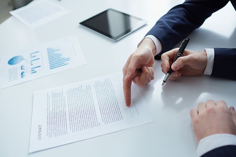 Un uomo indica un pezzo di carta mentre un altro uomo firma un documento.