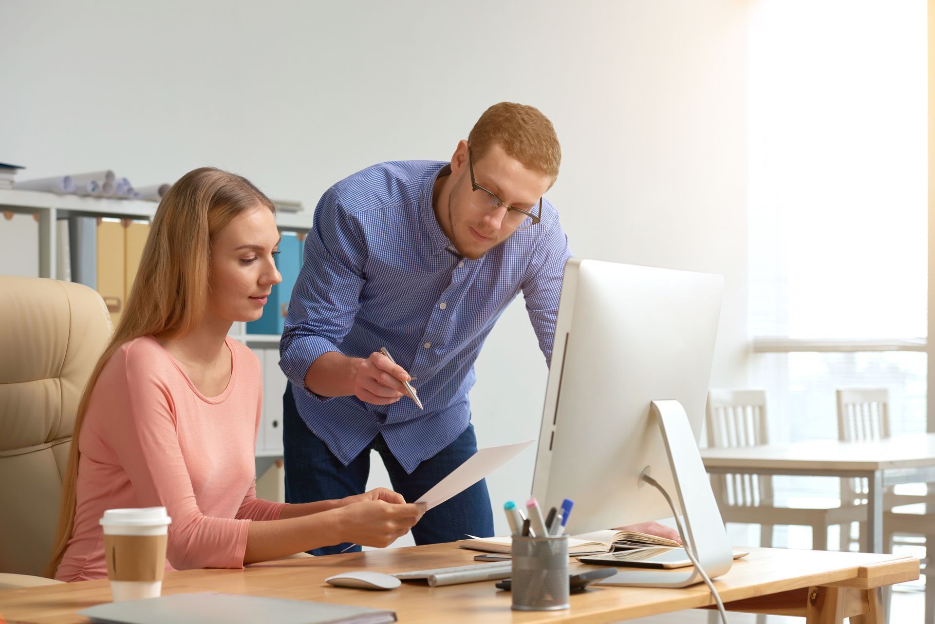 Un uomo e una donna stanno guardando lo schermo di un computer in un ufficio.