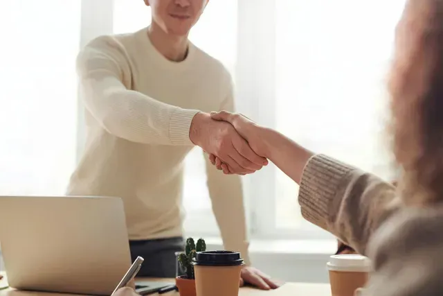 Un uomo e una donna si stringono la mano in un ufficio.