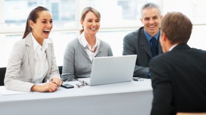 Un gruppo di persone è seduto a un tavolo con un computer portatile.