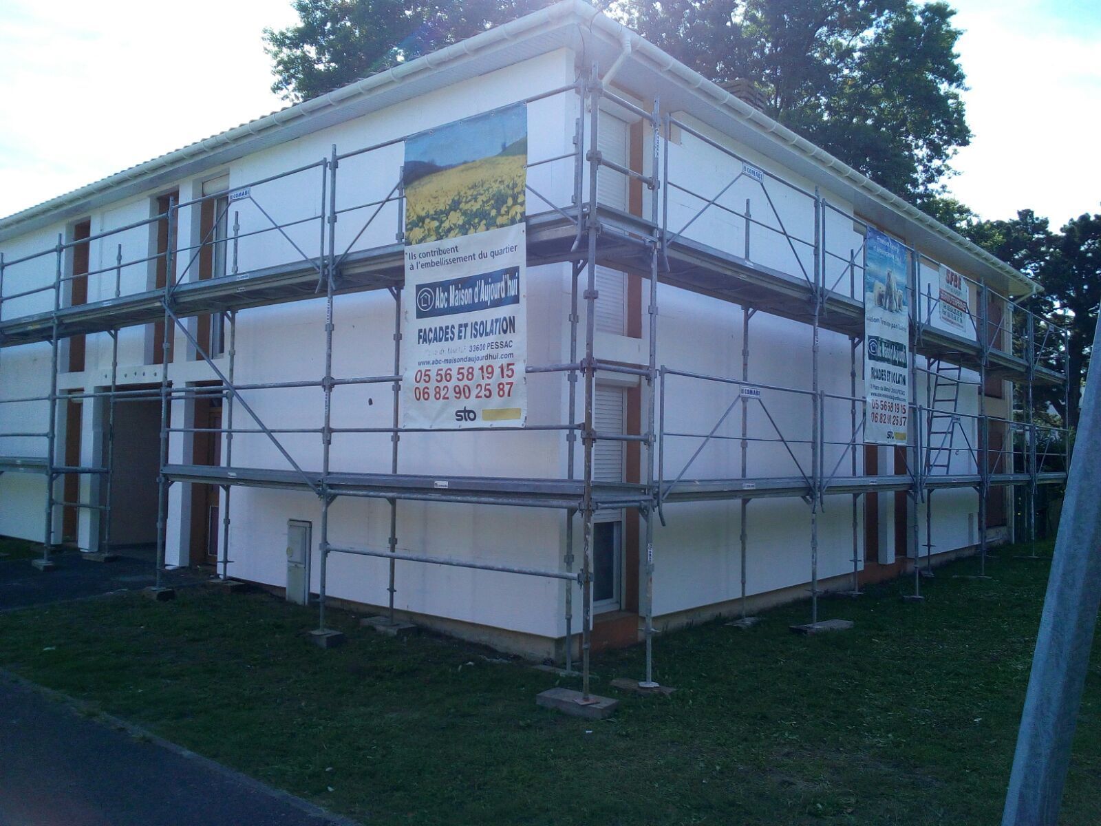 Un bâtiment blanc en cours de rénovation, avec des échafaudages métalliques entourant l'extérieur.