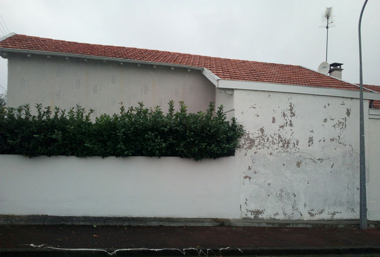 Un mur extérieur blanc d'une maison à la peinture écaillée, avant rénovation.