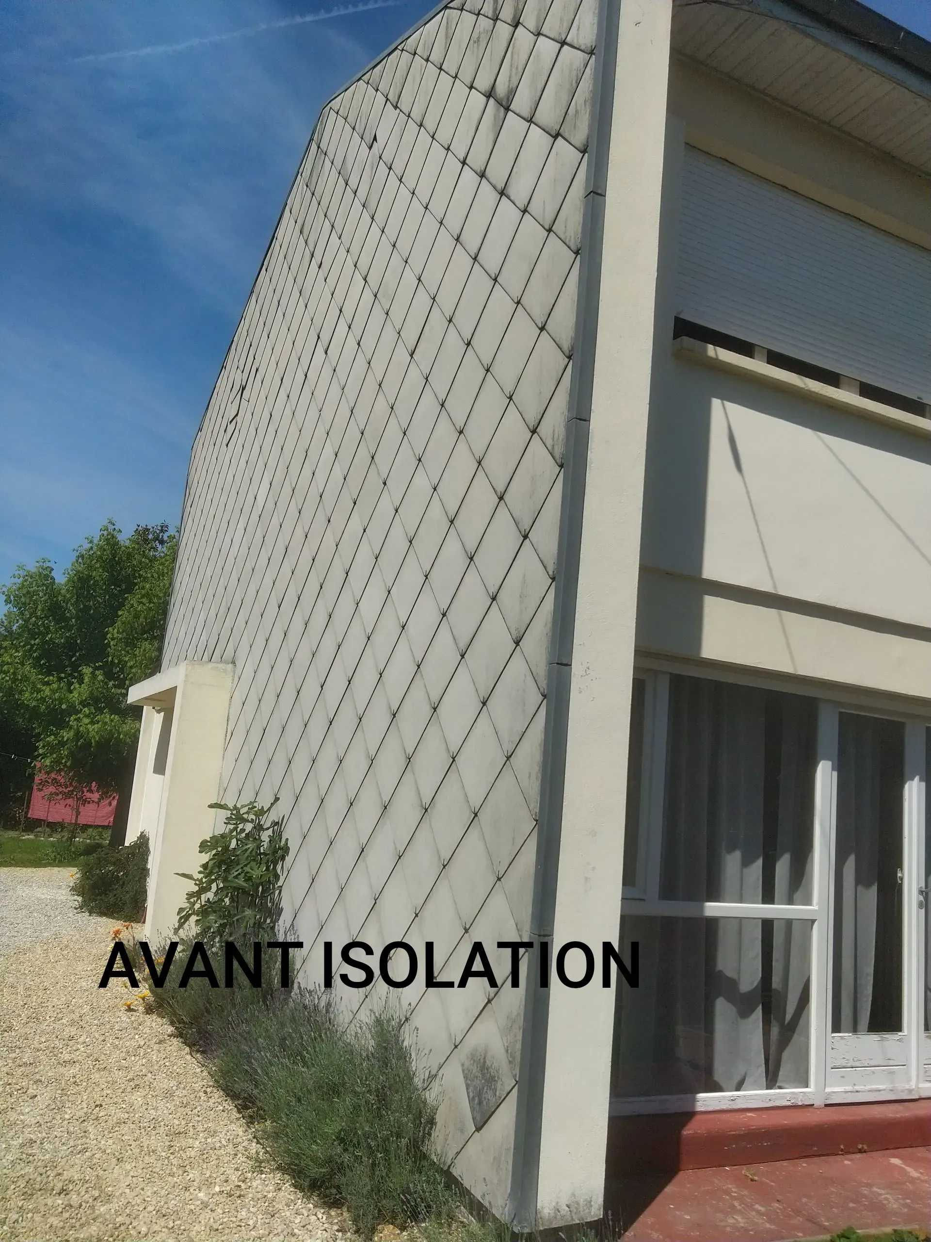Vue latérale de l'extérieur d'une maison montrant un mur en béton avec un motif en grille.