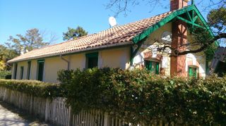Une maison de plain-pied avec un toit de tuiles en terre cuite, des murs jaunes et des boiseries vertes.