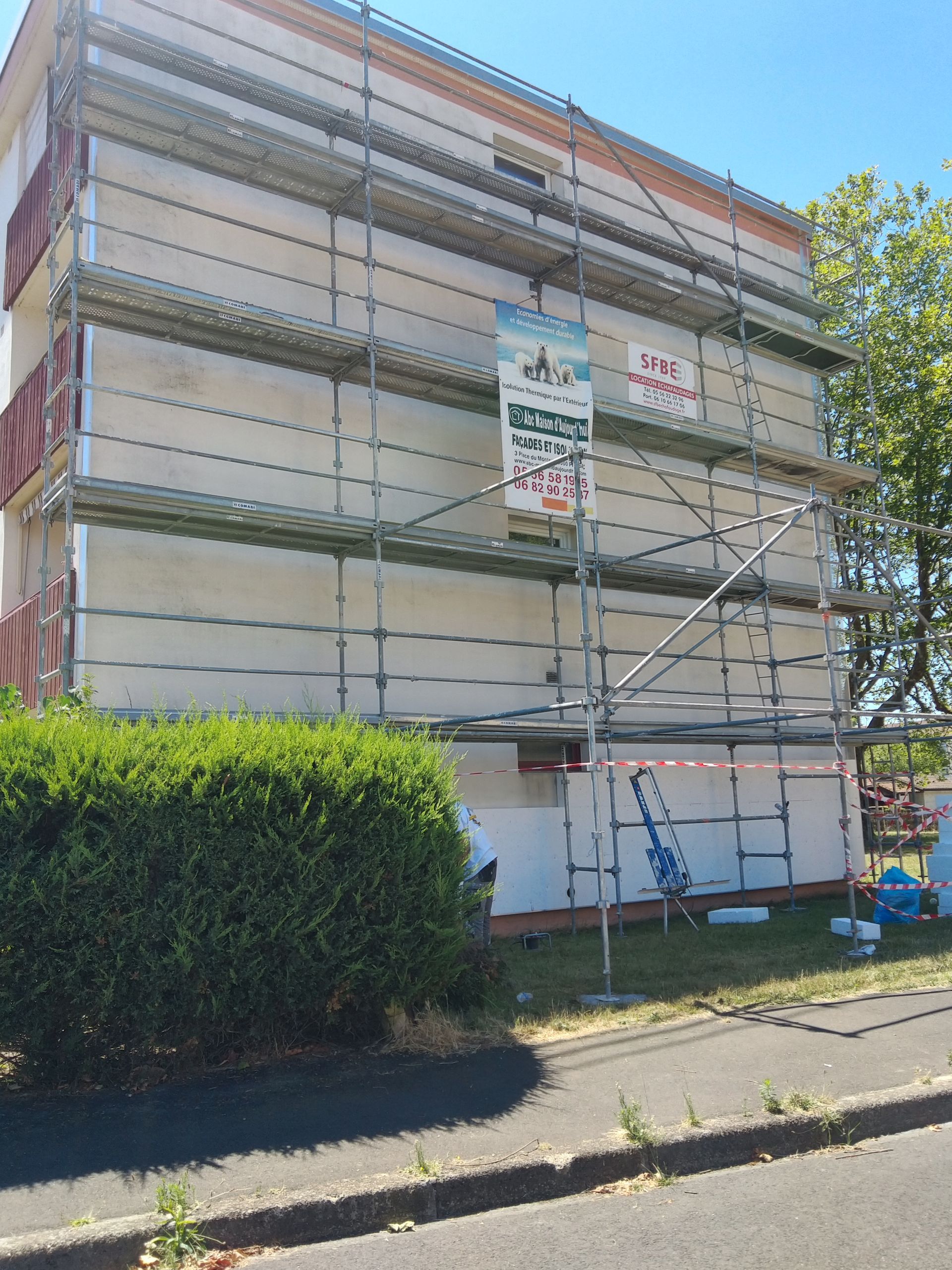 Un mur latéral nu d'un immeuble d'appartements à plusieurs étages, en cours de ravalement.