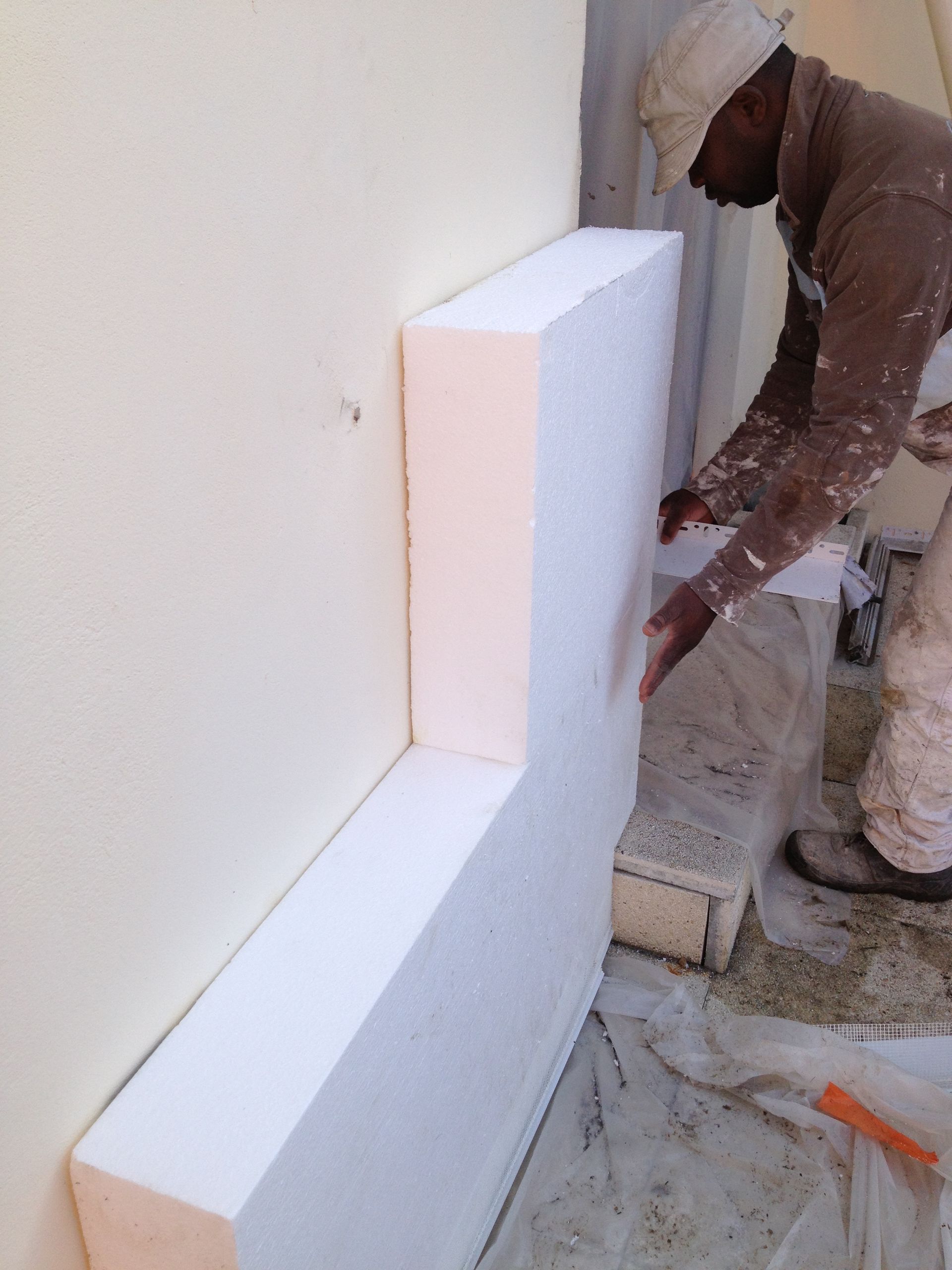 Une personne installe des panneaux d'isolation sur un mur extérieur.