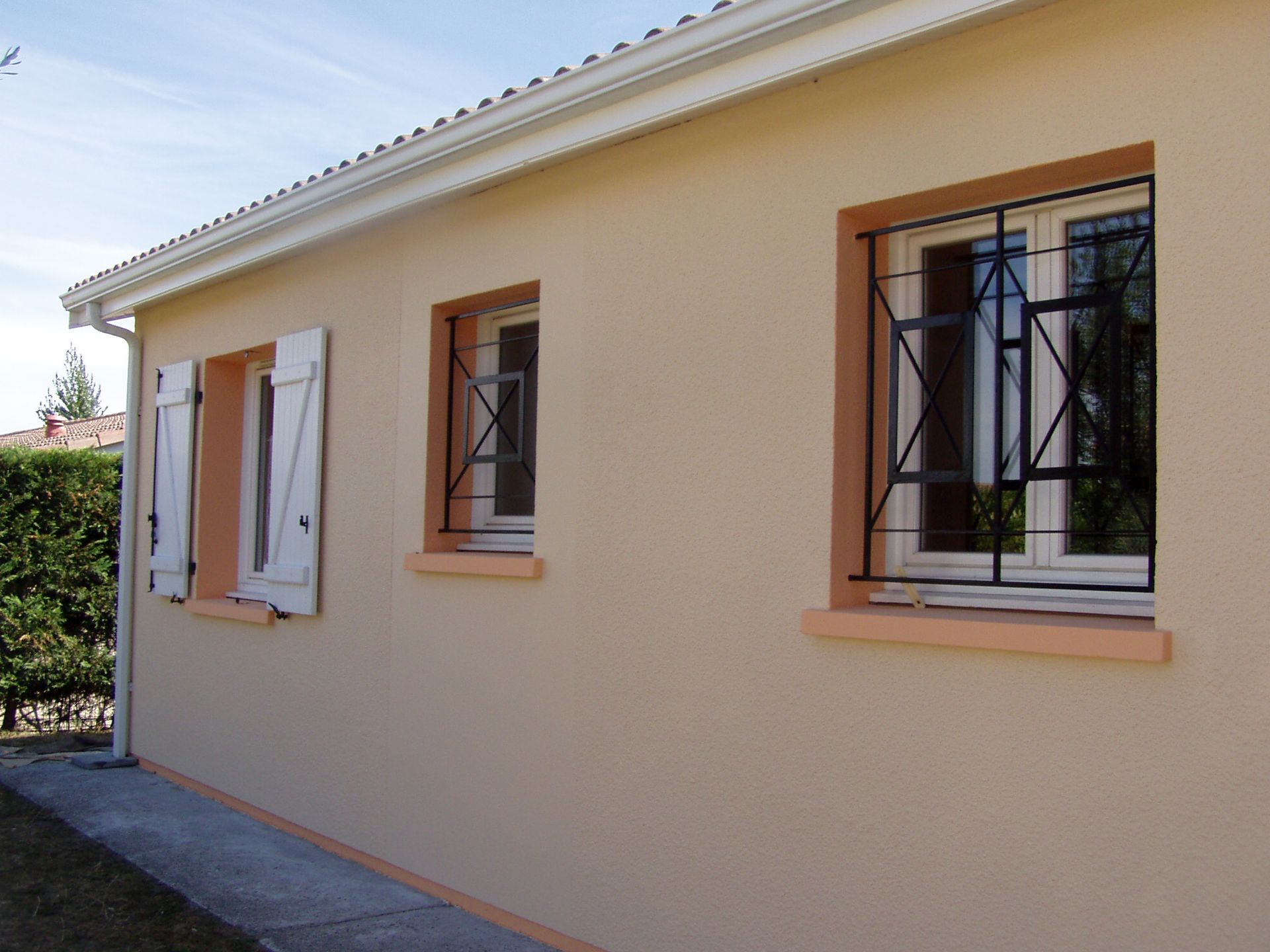 Mur extérieur beige d'une maison comportant deux petites fenêtres, après ravalement.