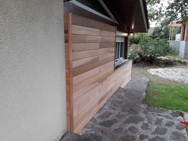 Vue latérale d'un mur de maison présentant un bardage horizontal en bois nouvellement installé.