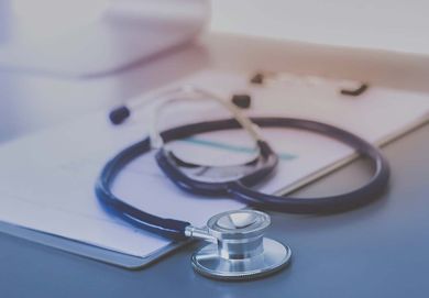 Un estetoscopio con un bolígrafo sobre un portapapeles, en un escritorio de un consultorio médico.