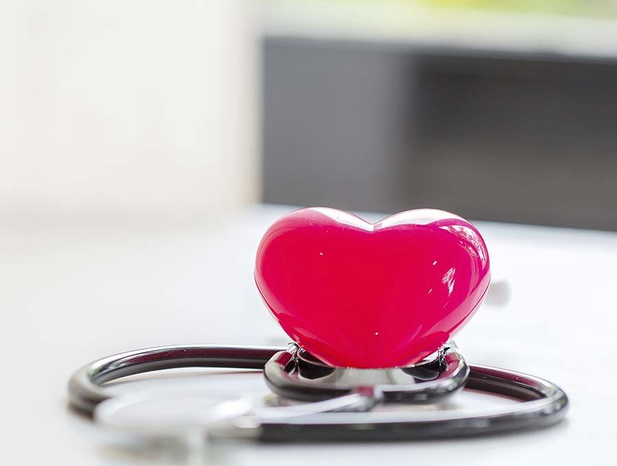 Amuleto rojo en forma de corazón en un estetoscopio, que simboliza la atención médica y el amor.