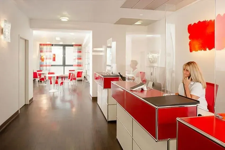 Eine Frau sitzt an einem rot-weißen Tresen in einer Lobby