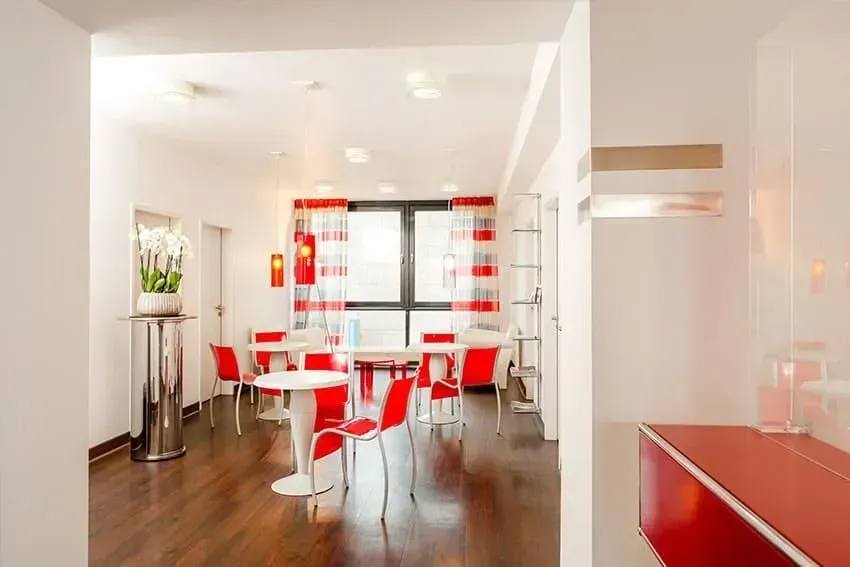 Ein Raum mit Tischen und Stühlen und einer roten Theke