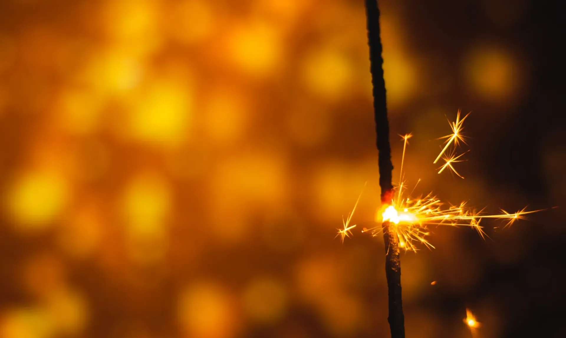 Bengala encendida con chispas brillantes sobre un fondo amarillo borroso.