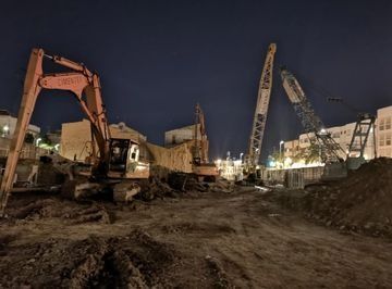 Una obra en construcción por la noche con mucha maquinaria