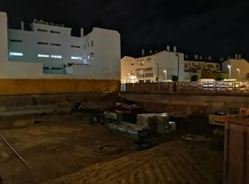 Una obra en construcción por la noche con un edificio al fondo.