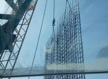 Una gran estructura metálica está siendo levantada por una grúa.