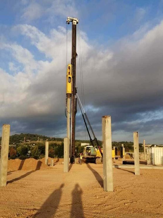Un sitio de construcción con una grúa amarilla al fondo