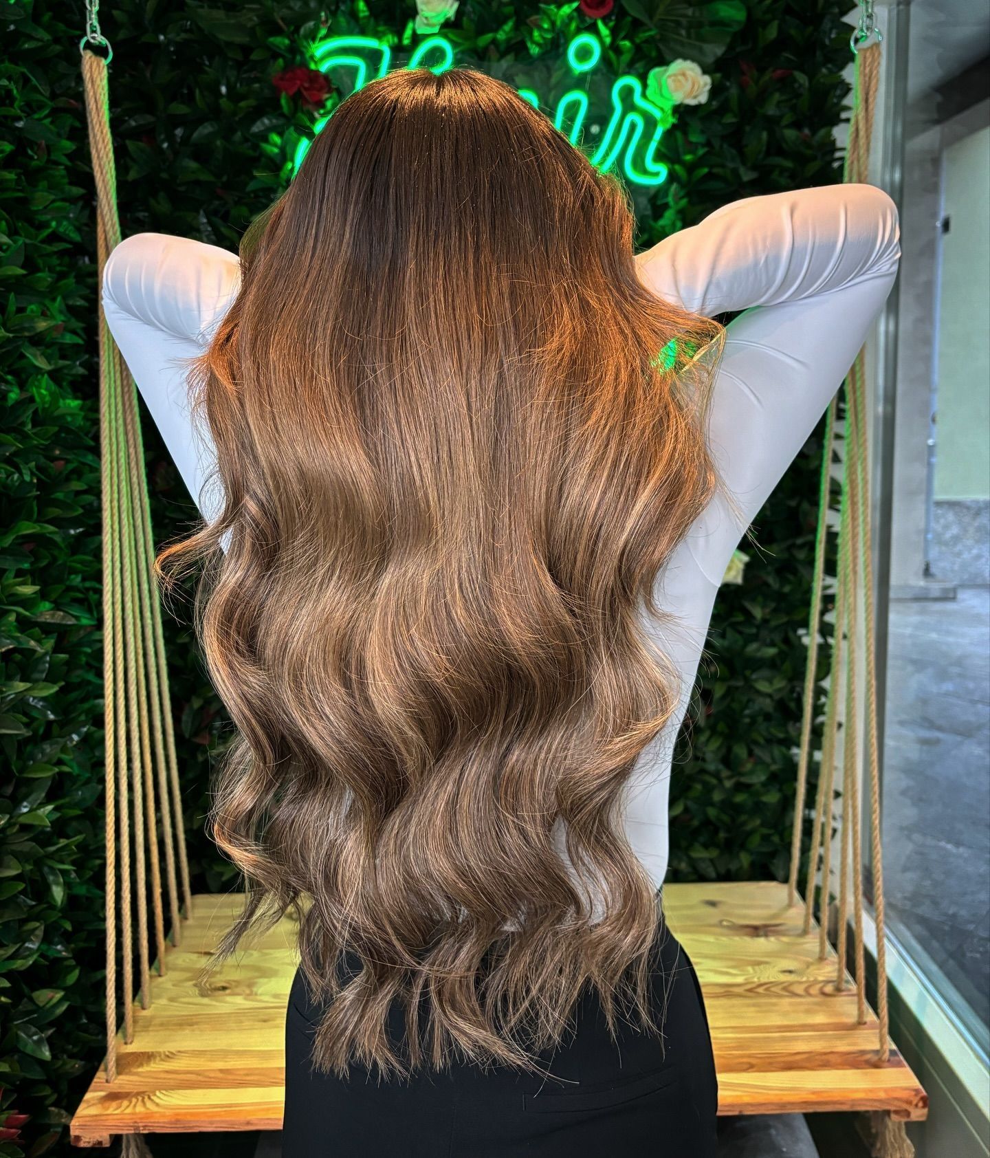 Eine Frau mit langen Haaren sitzt auf einer Holzschaukel.