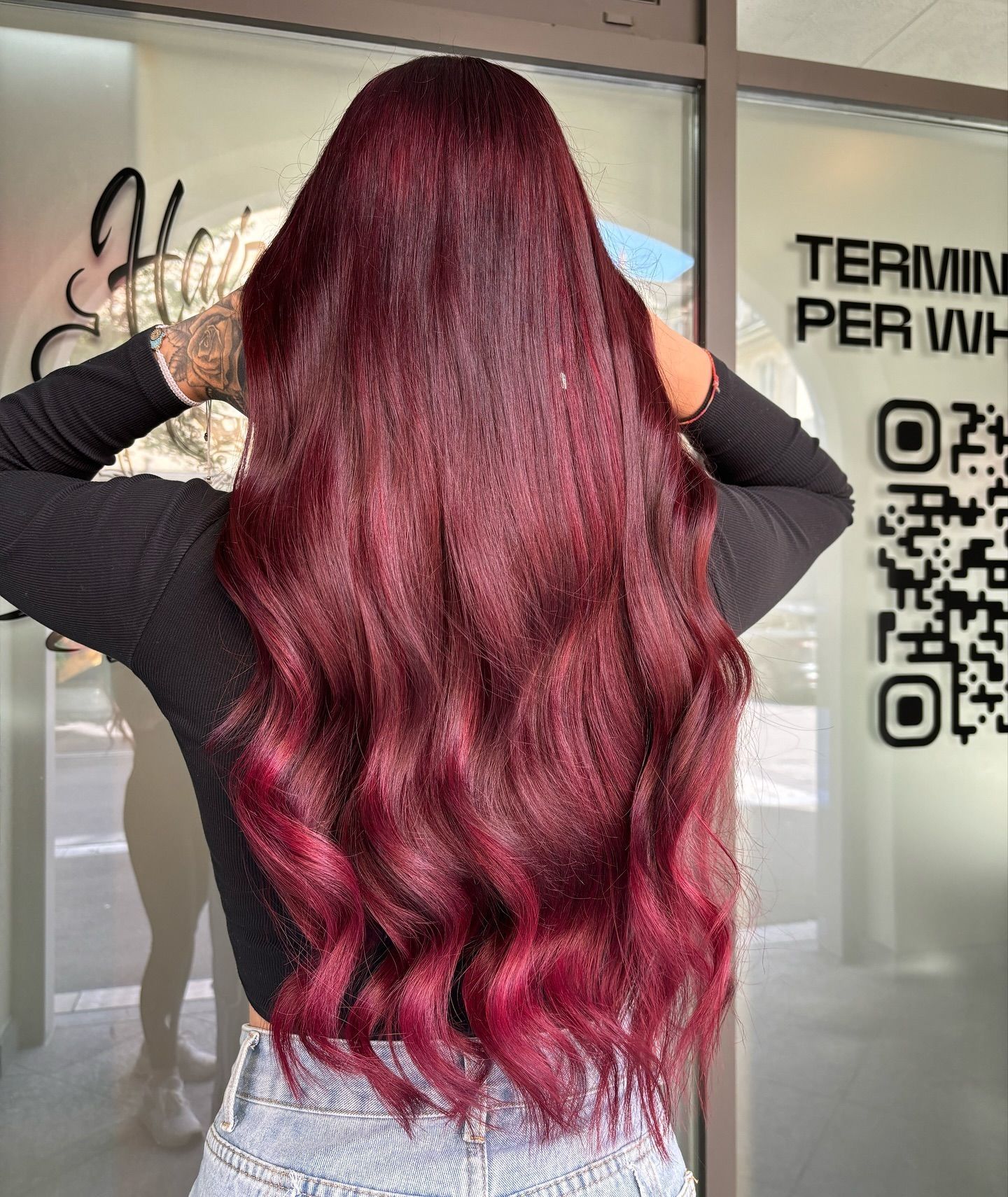 Eine Frau mit langen roten Haaren steht vor einem Gebäude.