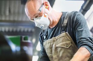 Mitarbeiter mit Atemschutzmaske bei Handwerkstätigkeit zum Schutz vor Staub und Partikeln
