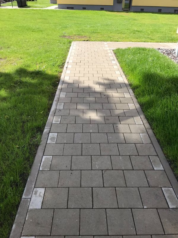 Gepflasterter Weg neben einer Wiese