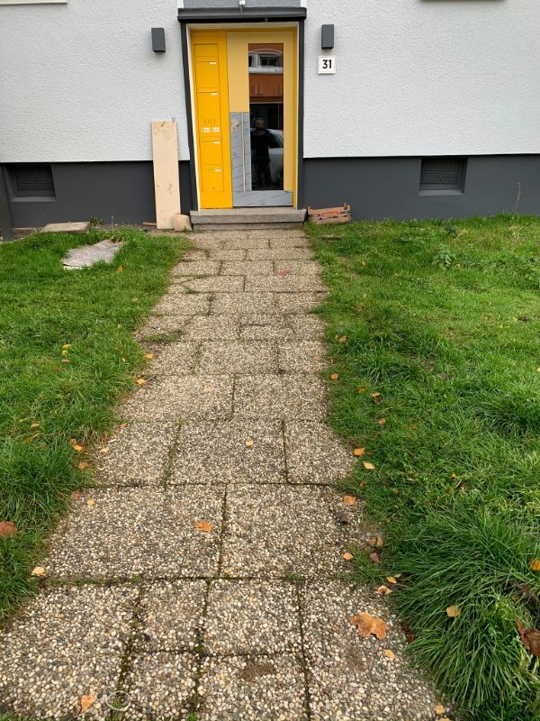 Gepflasterter Weg zu einer gelben Tür