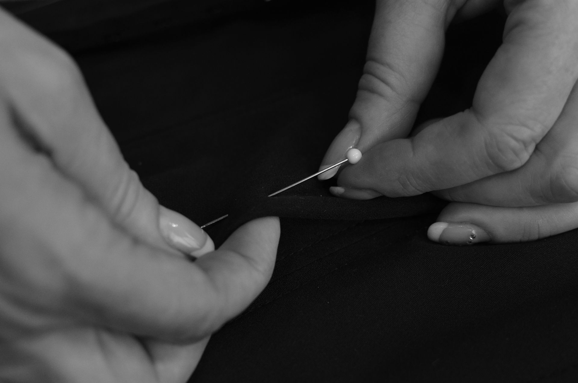 Hände halten Stoff mit Stecknadeln fest.