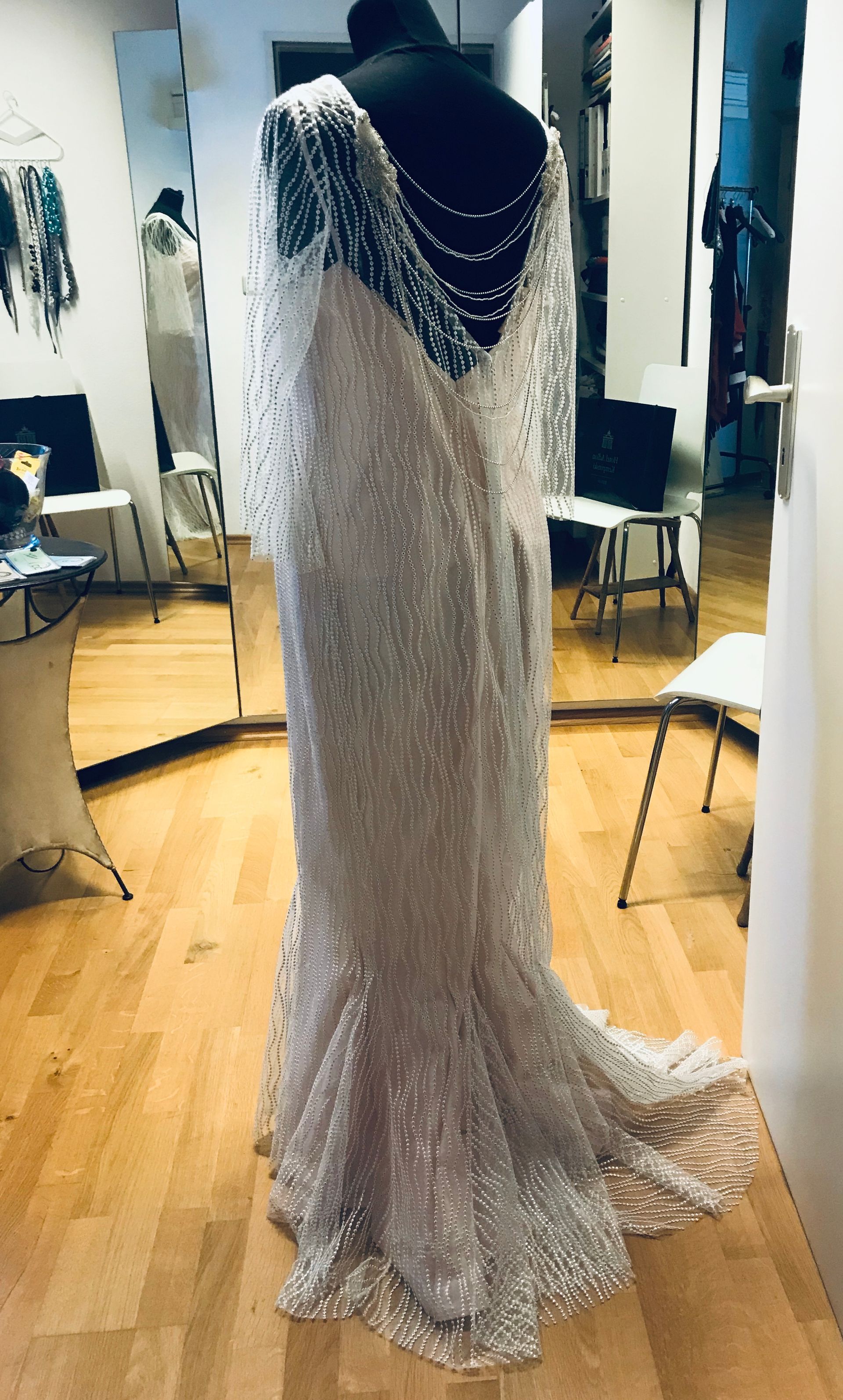 Brautkleid auf einer Schaufensterpuppe; schimmernder elfenbeinfarbener Stoff mit verziertem Rücken und langer Schleppe