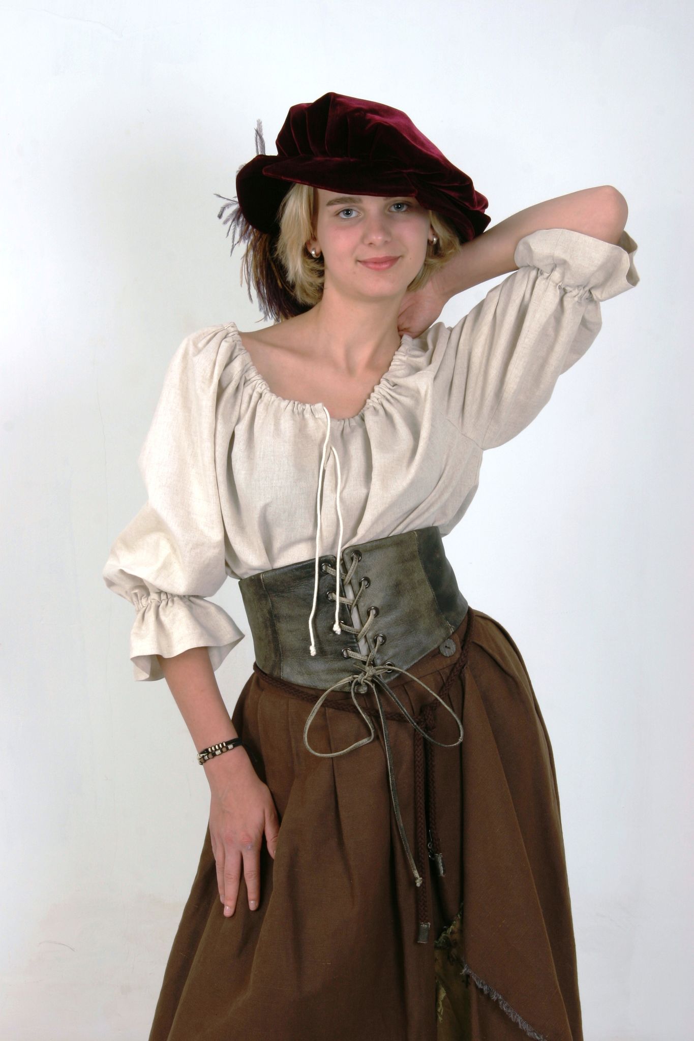 Frau in mittelalterlich anmutender Kleidung, bestehend aus braunem Rock, cremefarbener Bluse und bordeauxrotem Hut.