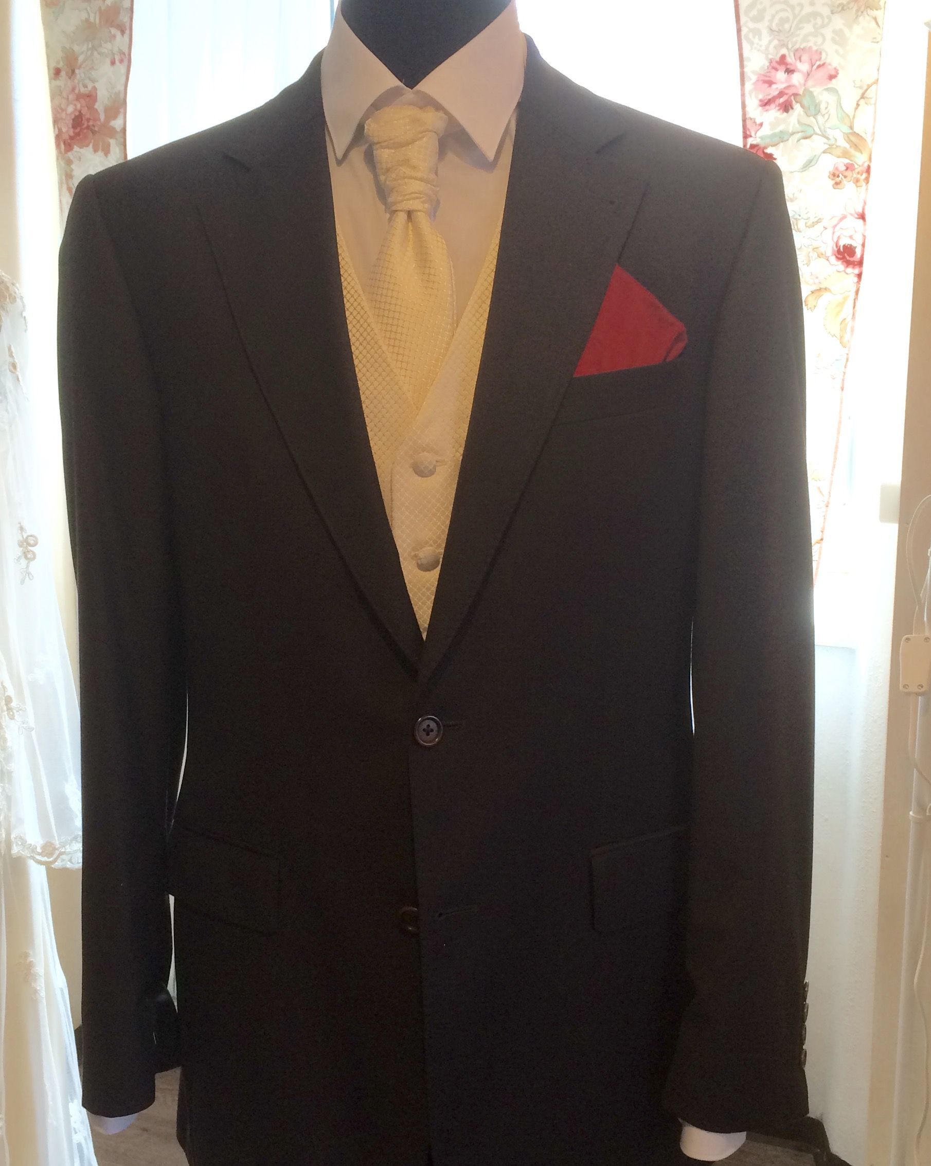 Dunkler Anzug an einer Schaufensterpuppe, dazu eine gelbe Weste, ein weißes Hemd und ein rotes Einstecktuch.