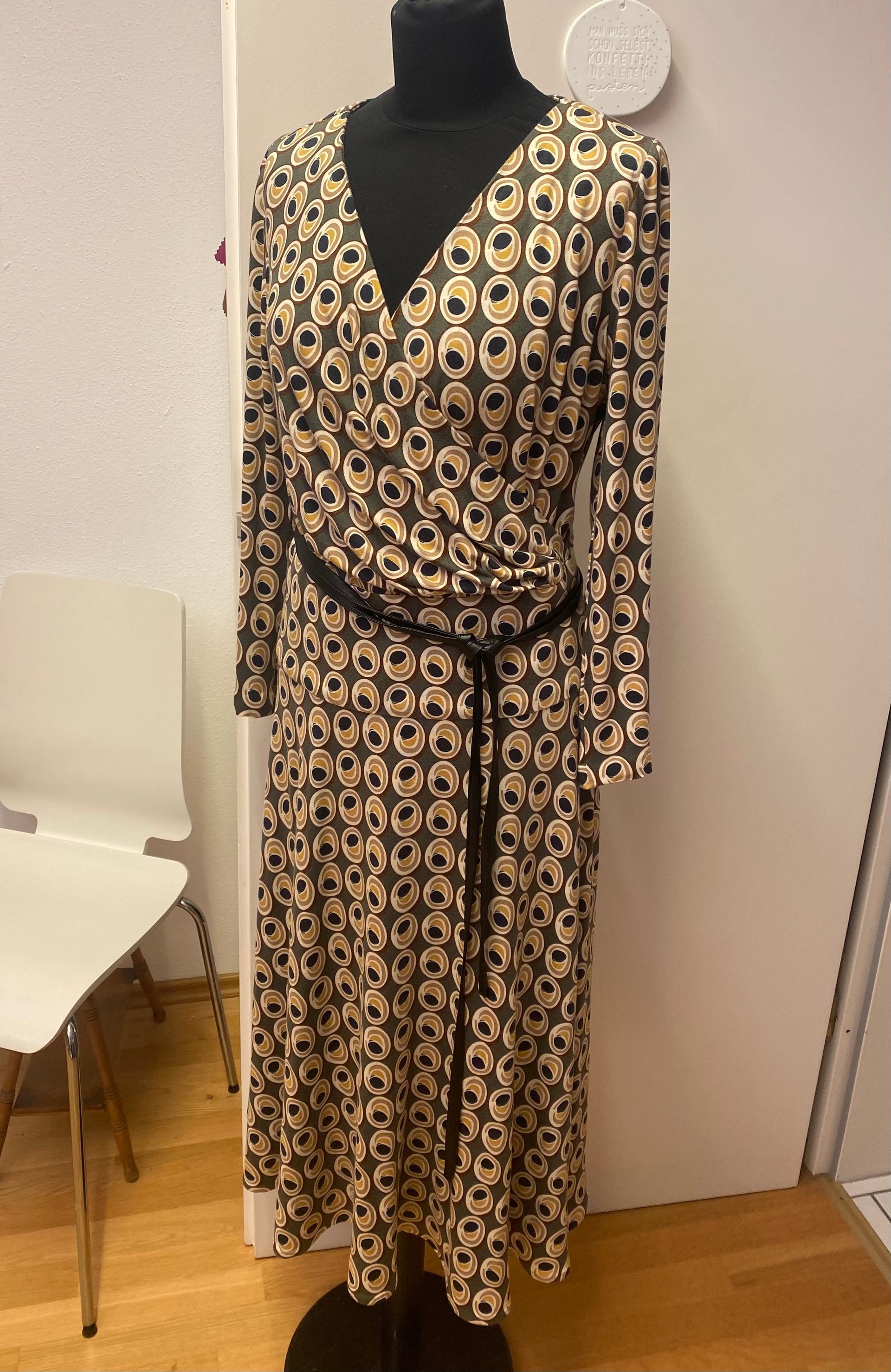 Kleid an einer Schaufensterpuppe; langärmelig, mit schwarzen und beigen Kreisen gemustert; schwarzer Gürtel; Halbtotale.