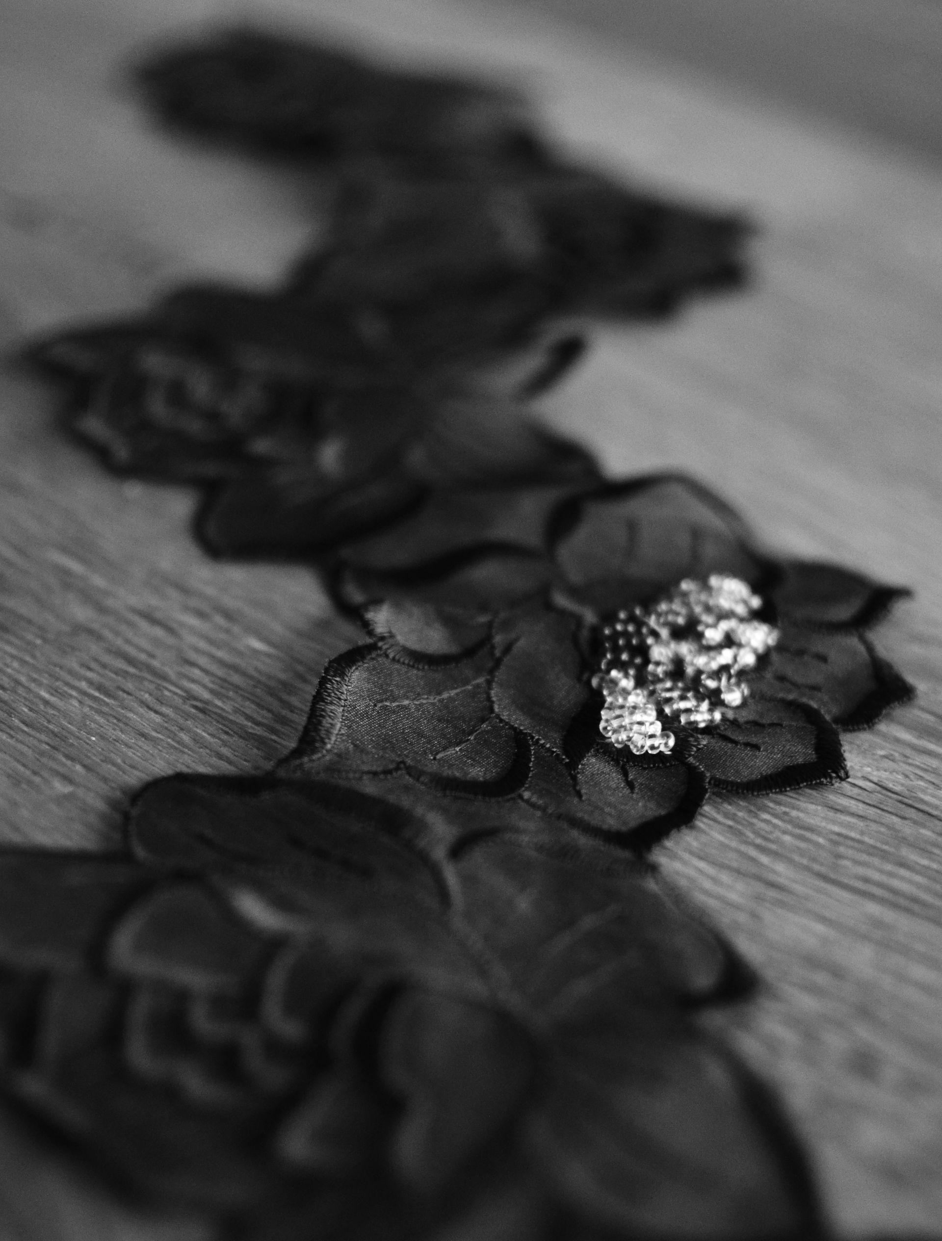 Schwarzer Blumengirlande auf Holzoberfläche mit strukturierter Mitte.